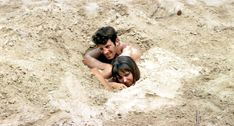 Eine Frau und ein Mann sind bis zum Hals im Sand vergraben.