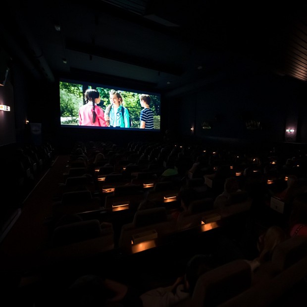 Eine Gruppe Schüler*innen schaut in einem Kinosaal einen Film auf einer Leinwand.