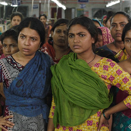 Frauen in einer Nähfabrik stehen zusammen mit den Händen in den Hüften.