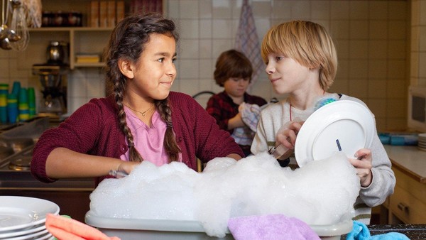 Ein Mädchen und ein Junge spülen Geschirr und schauen sich gegenseitig an.