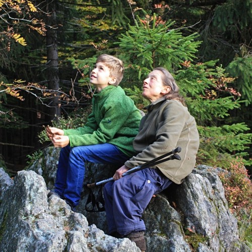 Ein Junge und eine alte Frau sitzen auf einem Stein.