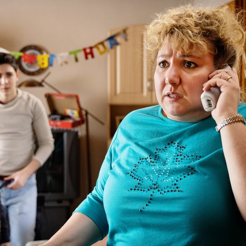 Eine Frau am Telefon, im Hintergrund ihre Söhne