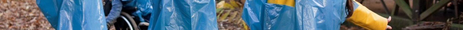 Vier Kinder tanzen in blauen Regenmänteln durch den Wald.