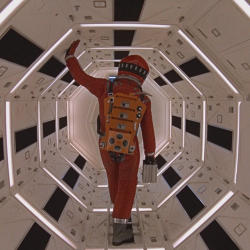 Ein Astronaut von hinten, der durch eine Raumstation geht.