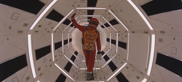 Ein Astronaut in voller Montur von hinten, wie er durch ein Raumschiff geht.