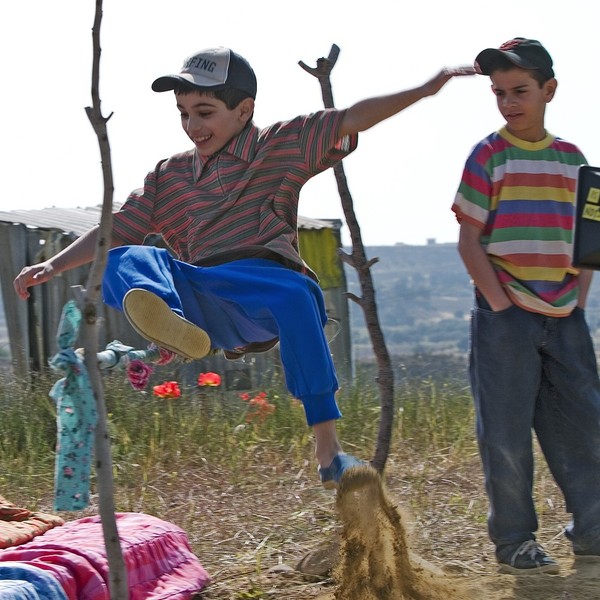 Ein Junge springt über eine Latte aus Holz.