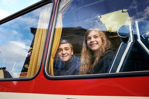 Ein Junge und ein Mädchen blicken aus einem Busfenster.
