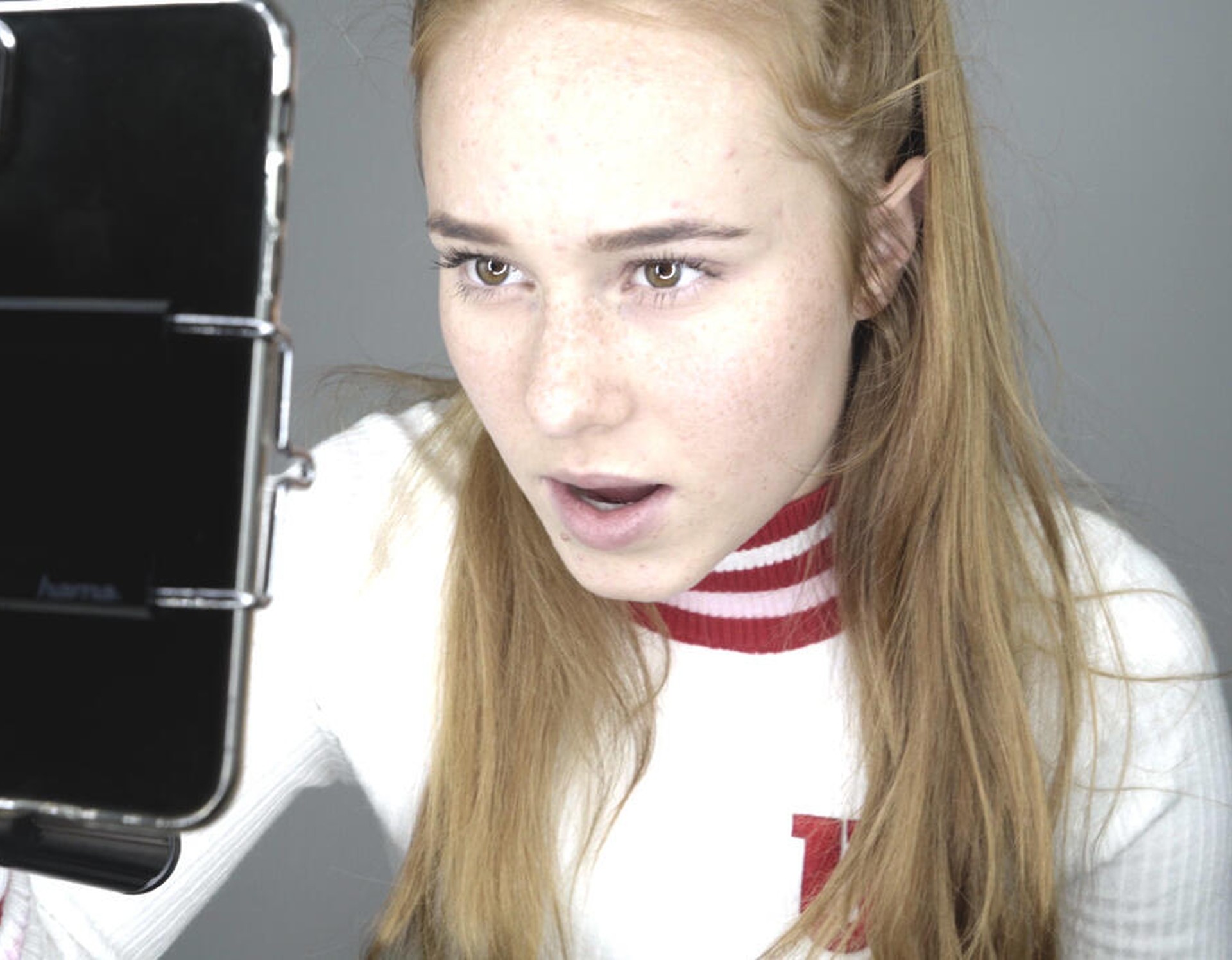 Ein junges Mädchen nimmt sich selbst mit dem Smartphone auf.
