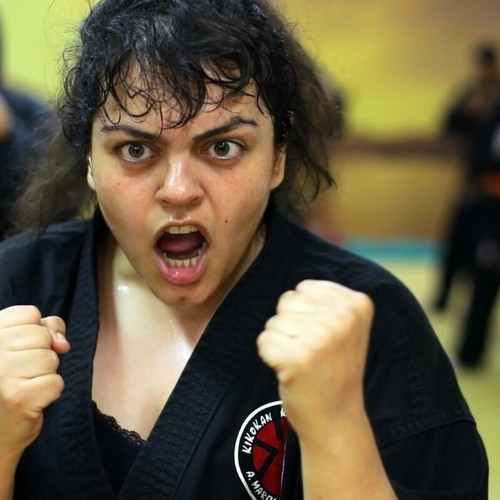 Eine Frau ballt ihre Fäuste und schreit beim Karatetraining.