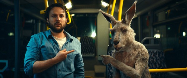 Ein Mann und ein Känguru stehen in einem Bus und zeigen aufeinander.