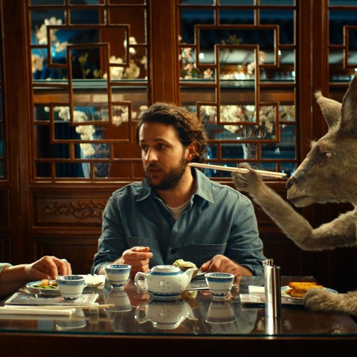 Zwei Männer und ein Känguru sitzen an einem Tisch.