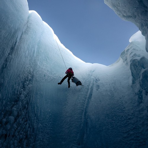 Ein Mann seilt sich in eine Gletscherspalte ab.